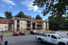 Professional roof cleaning crew setting up safety equipment at a large apartment complex